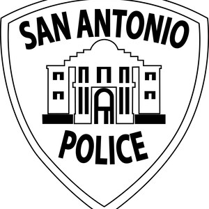 May include: A black and white San Antonio Police badge. The shield-shaped emblem features the words "SAN ANTONIO" above a stylized building and the word "POLICE" below. The design is simple and bold.