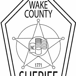 May include: Black and white Wake County Sheriff badge. The badge features a five-pointed star, a circle, and the text "WAKE COUNTY SHERIFF" and "1771". The North Carolina flag is in the centre.