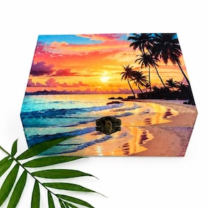May include: A rectangular wooden box featuring a vibrant sunset beach scene with palm trees, ocean waves, and a golden sky. The box has a dark metal latch on the front center. A single green palm leaf is positioned in front of the box.