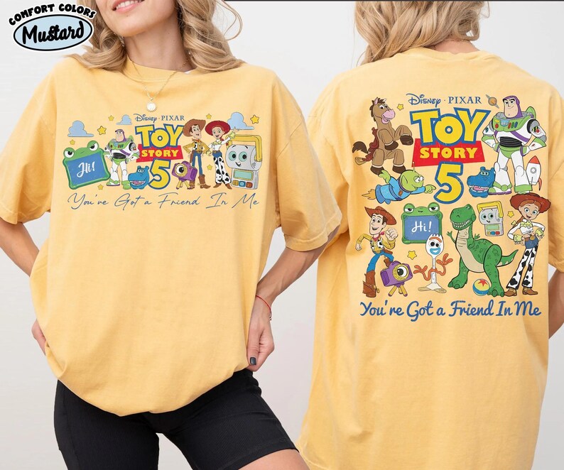 Może przedstawiać: Musztardowa koszulka z grafiką postaci z filmu Disneya Pixara Toy Story. Prz&oacute;d koszulki przedstawia napis "Toy Story 5" i "You've Got a Friend In Me". Tył koszulki r&oacute;wnież ma grafikę Toy Story.