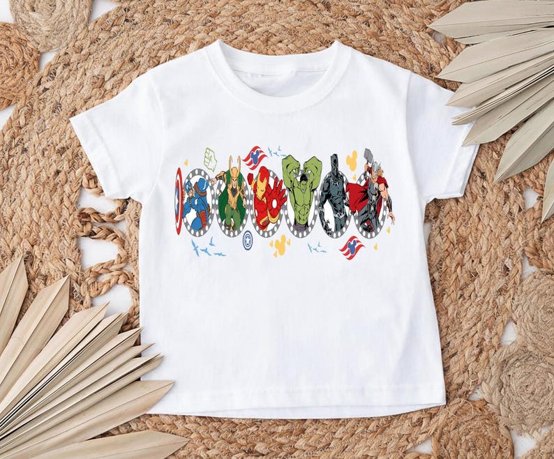 Puede incluir: Camiseta blanca con un gr&aacute;fico colorido de superh&eacute;roes en marcos ovalados. El dise&ntilde;o incluye al Capit&aacute;n Am&eacute;rica, Thor, Iron Man y otros. La camiseta est&aacute; hecha de un material suave y es adecuada para ni&ntilde;os.