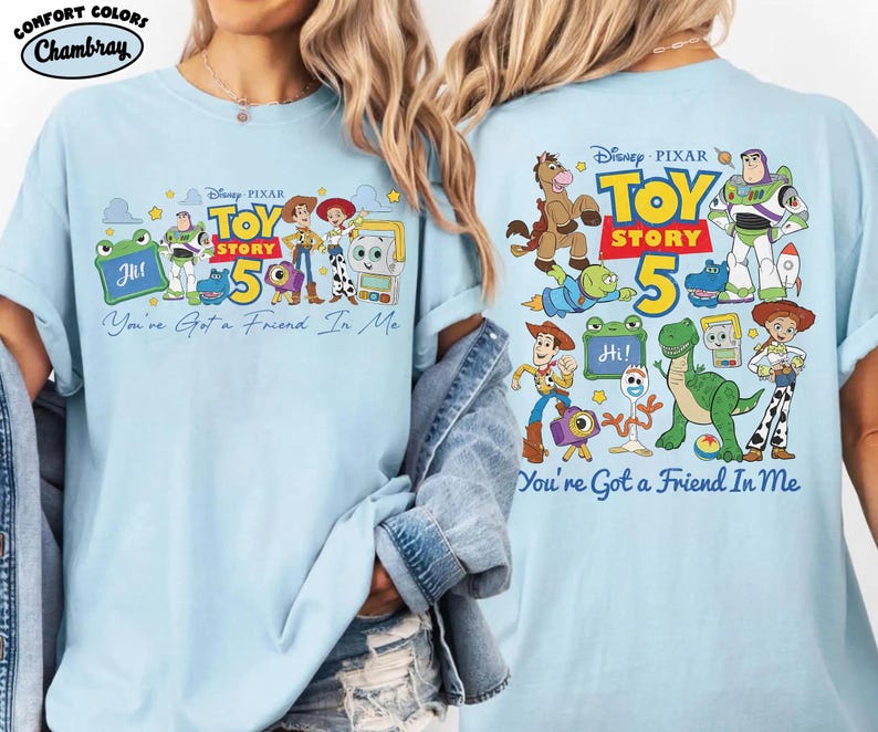 Może przedstawiać: Jasnoniebieska koszulka z nadrukiem z Toy Story, przedstawiającym postacie takie jak Woody i Buzz Lightyear. Widoczne są napisy "TOY STORY 5" i "You've Got a Friend In Me". Koszulka wykonana jest z miękkiego materiału.