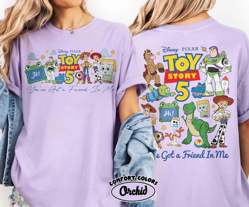 Może przedstawiać: Jasnofioletowa koszulka z motywem Toy Story 5. Prz&oacute;d koszulki przedstawia postacie i napis "You've Got a Friend In Me". Tył r&oacute;wnież zawiera logo Toy Story 5 i postacie. Koszulka jest z Comfort Colors, w kolorze Orchid.
