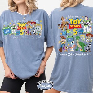 Może przedstawiać: Jasnoniebieska koszulka z motywem z filmu Disneya i Pixara Toy Story. Prz&oacute;d koszulki przedstawia napis "Toy Story 5" i postacie. Tył koszulki r&oacute;wnież zawiera ten sam wz&oacute;r i frazę "You're Got a Friend In Me."