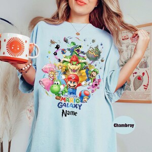 Puede incluir: Una taza de cer&aacute;mica blanca con un asa negra y el texto "But First, Coffee" en negrita negra. La taza est&aacute; sobre una superficie de madera. La taza mide aproximadamente 10 cm de alto.