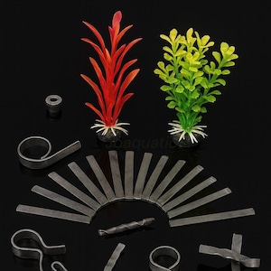 May include: An assortment of aquarium decorations and accessories against a black background. The image includes two artificial plants, one red and one green, along with various metal pieces, including rings and bars, likely for aquarium use.