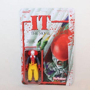 Puede incluir: Figura de acción de Pennywise el payaso de la película "IT", en un blíster. El embalaje presenta el título de la película en rojo, un globo rojo y una combinación de colores rojo y blanco. La figura lleva un disfraz de payaso.