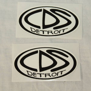 May include: Two white oval stickers with black outlines. The stickers feature the text "CDS DETROIT" and a stylized black "CDS" logo.