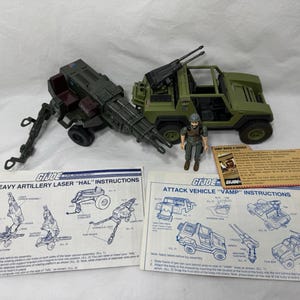 Può includere: Un veicolo d'attacco G.I. Joe VAMP verde, un laser per artiglieria pesante HAL verde scuro, una piccola action figure e due fogli di istruzioni. Il veicolo presenta un design aperto, mentre l'unità di artiglieria include una piattaforma rotante.