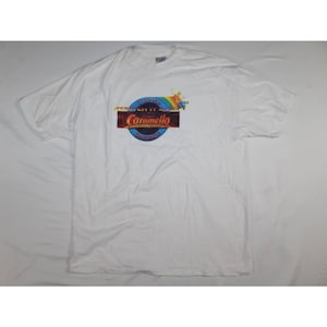 May include: White t-shirt with a colorful graphic of a person riding a rollercoaster with the text "Stretch It Out" and "Caramello" in a circle.