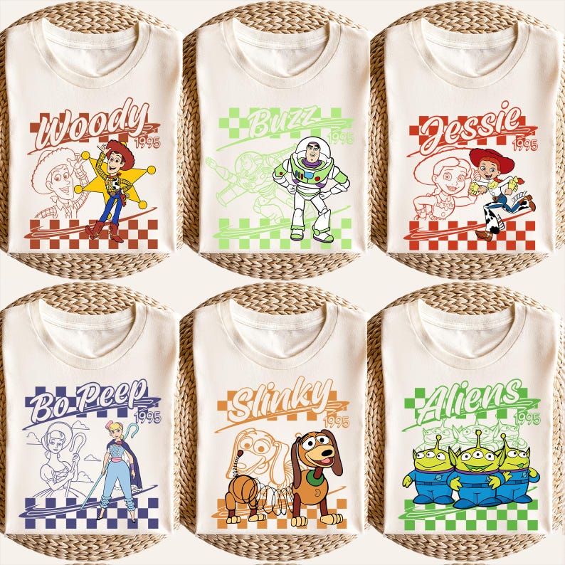 May include: Six cream-colored t-shirts featuring Toy Story characters. Each shirt has a different character design: Woody, Buzz, Jessie, Bo Peep, Slinky, and Aliens. Each design includes the character's name and the year 1995.