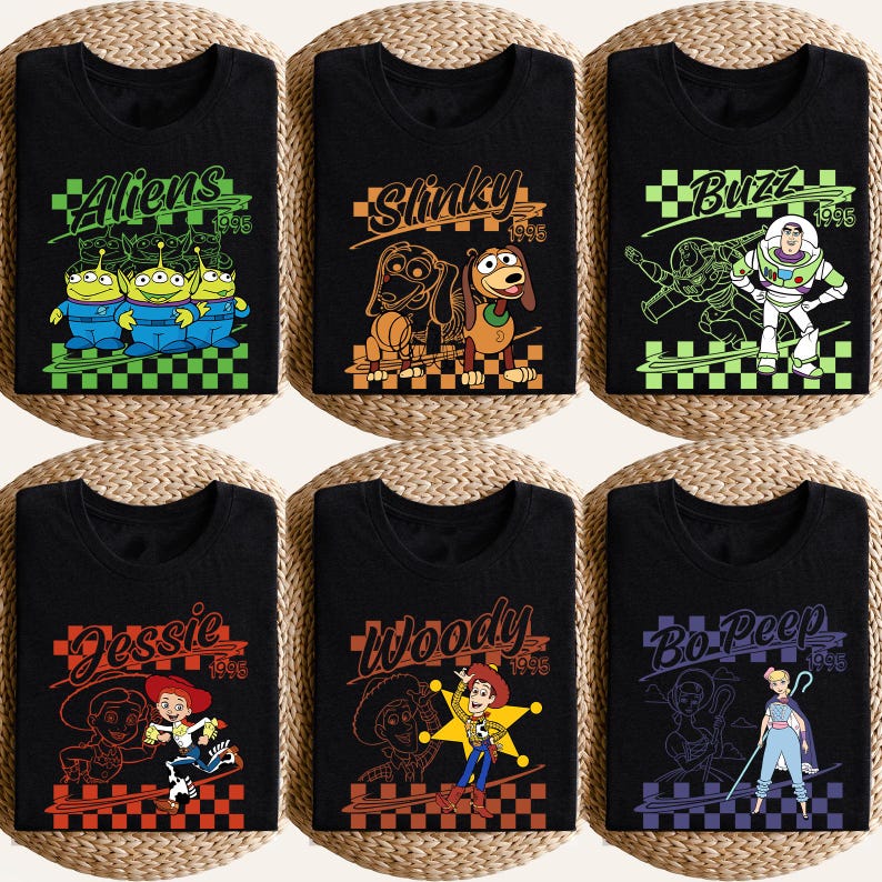 May include: Six black t-shirts featuring characters from the animated film Toy Story. Each shirt has a different character design, including Aliens, Slinky, Buzz, Jessie, Woody, and Bo-Peep, with the year 1995.