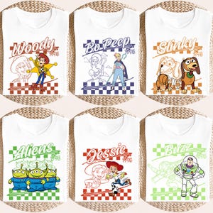 May include: White t-shirts featuring various characters from the animated film Toy Story. Each shirt displays a character's name and the year 1995, with designs including Woody, Bo-Peep, Slinky, Aliens, Jessie, and Buzz Lightyear.