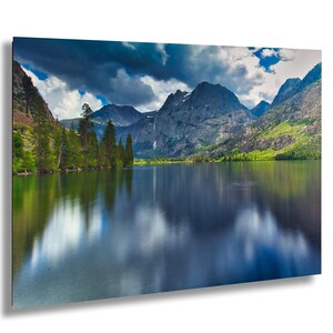 Puede incluir: Impresión de un paisaje sereno con un lago que refleja montañas y cielo. La imagen muestra un lago azul vibrante, árboles verdes y nubes dramáticas, creando una escena tranquila. Ideal para la decoración del hogar.