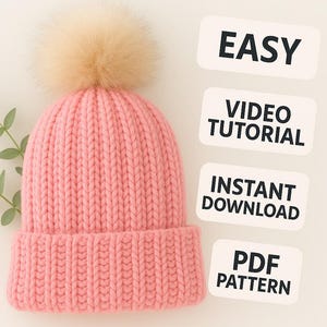 May include: A pink knit beanie with a large, fluffy, light brown pom-pom on top. The hat has a ribbed brim and a textured knit pattern. Text on the right side reads "EASY", "VIDEO TUTORIAL", "INSTANT DOWNLOAD", and "PDF PATTERN".