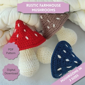 May include: A collection of crocheted mushrooms in red, brown, blue, and cream colors. The mushrooms have white spots and are in various sizes. The image includes text that reads "Rustic Farmhouse Mushrooms," "PDF Pattern," "Digital Download," and "Mushrooms in 3 Sizes."