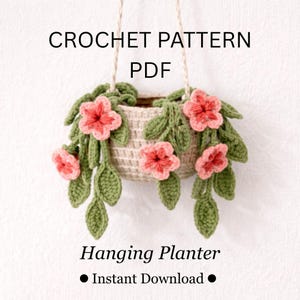 May include: A crocheted hanging planter with pink flowers and green leaves. The planter is beige and suspended by a white cord. Text on the image reads "CROCHET PATTERN PDF" and "Hanging Planter".
