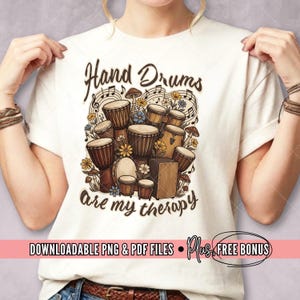 May include: Cream-coloured t-shirt with a graphic of hand drums, musical notes, flowers, and mushrooms. The text "Hand Drums are my therapy" is displayed above the graphic. The bottom of the shirt includes the text "DOWNLOADABLE PNG & PDF FILES • Plus FREE BONUS".