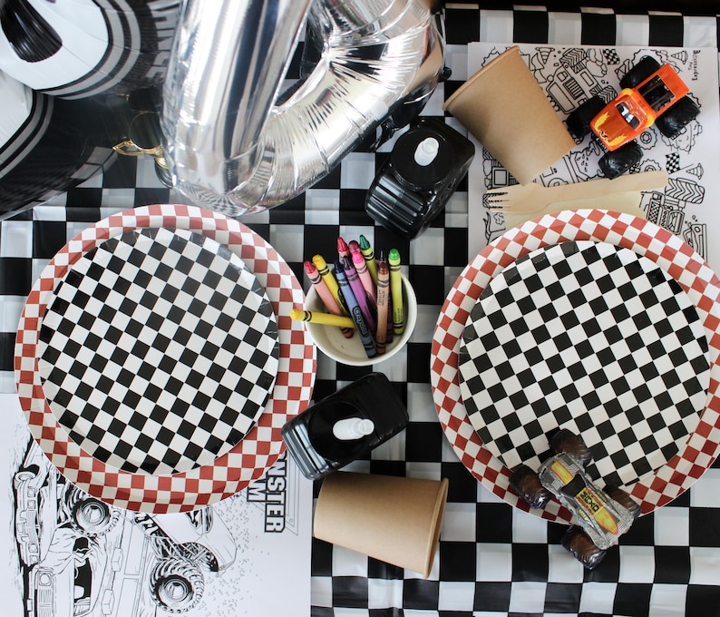 Op de afbeelding: Een feesttafel met een zwart-wit geblokt thema. Inclusief geblokte borden, kleurpotloden, speelgoed monstertrucks en een zilveren cijferballon. De tafel is gedekt voor een raceauto- of monstertruck-themafeest.
