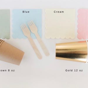 Op de afbeelding: Een assortiment feestartikelen, waaronder saliegroene, blauwe, cr&egrave;mekleurige en roze servetten met geschulpte randen. Houten vorken en bruine bekers van 237 ml worden getoond met gouden bekers van 355 ml. De tekst "Sage", "Blue", "Cream", "Pink", "Brown 8 oz" en "Gold 12 oz" is inbegrepen.