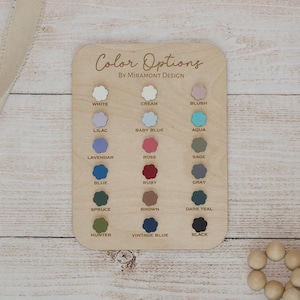 May include: A wooden colour chart with the text "Color Options by Miramont Design" and a selection of colour swatches. Colours include white, cream, blush, lilac, baby blue, aqua, lavender, rose, sage, blue, ruby, grey, spruce, brown, dark teal, hunter, vintage blue, and black.