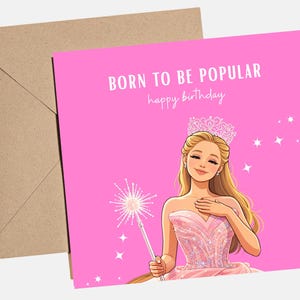 May include: A pink birthday card with the text "BORN TO BE POPULAR happy birthday." The card features an illustration of a blonde woman wearing a tiara and a pink dress, holding a wand. A brown envelope is behind the card.
