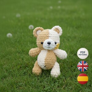 Puede incluir: Un oso de peluche tejido a mano con un diseño bicolor, en tonos beige y crema. El oso tiene una nariz negra, detalles cosidos y una pequeña flor amarilla. El oso está sobre hierba verde. También se ve el texto "PDF PATTERNS".
