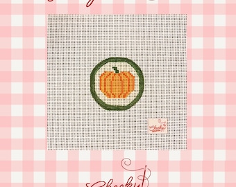 May include: A square needlepoint canvas featuring a central orange pumpkin graphic enclosed within a dark green circular border. The canvas includes a small square logo tag labeled Cheeky Needlepoint. The text Needlepoint Canvas appears above.