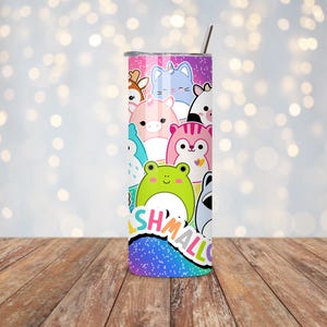 May include: A colorful tumbler featuring a variety of cartoon animal characters. The design includes a deer, cat, pig, frog, and other creatures. The word "SHMALLOW" is printed on the bottom. The tumbler has a silver lid and a straw.