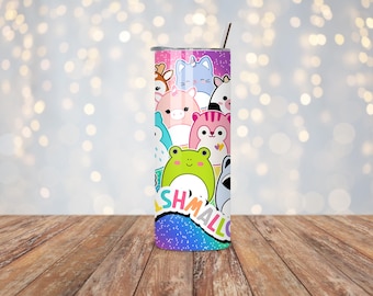 May include: A colorful tumbler featuring a variety of cartoon animal characters. The design includes a deer, cat, pig, frog, and other creatures. The word "SHMALLOW" is printed on the bottom. The tumbler has a silver lid and a straw.