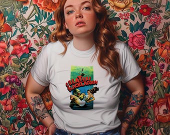 May include: White t-shirt featuring a vintage movie poster graphic for "Creature from the Black Lagoon." The graphic is in a rectangular frame with a green and blue background. The shirt is paired with blue jeans.