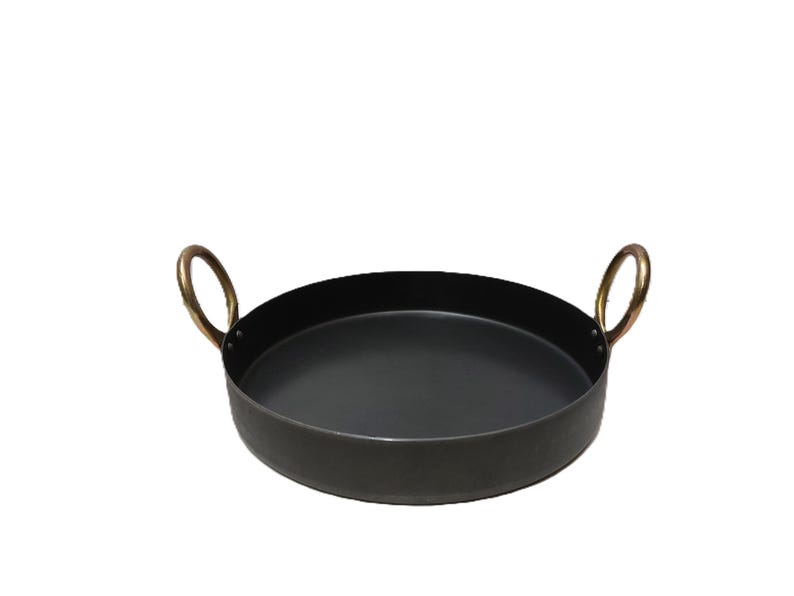 May include: A round, black metal serving tray with two brass-colored handles. The tray is approximately 14 inches in diameter and is suitable for serving food or displaying items. The handles are curved and add a decorative touch.