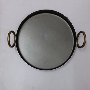 Peut inclure: Plateau rond en m&eacute;tal avec int&eacute;rieur argent&eacute; et bord noir. Il est &eacute;quip&eacute; de deux poign&eacute;es dor&eacute;es. Ce plateau est con&ccedil;u pour le service ou la pr&eacute;sentation.