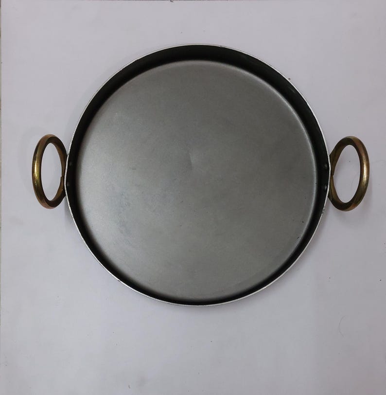 Peut inclure: Plateau rond en m&eacute;tal avec int&eacute;rieur argent&eacute; et bord noir. Il est &eacute;quip&eacute; de deux poign&eacute;es dor&eacute;es. Ce plateau est con&ccedil;u pour le service ou la pr&eacute;sentation.