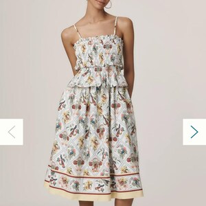 May include: A light blue and white floral dress. The dress features a smocked bodice, spaghetti straps, and a tiered skirt. The hemline falls just below the knee.