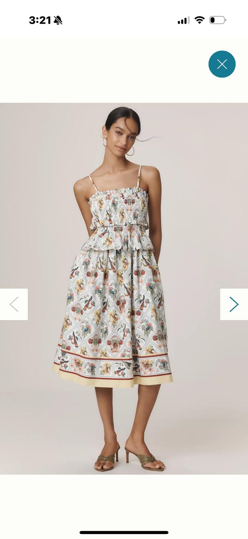 May include: A light blue and white floral dress. The dress features a smocked bodice, spaghetti straps, and a tiered skirt. The hemline falls just below the knee.