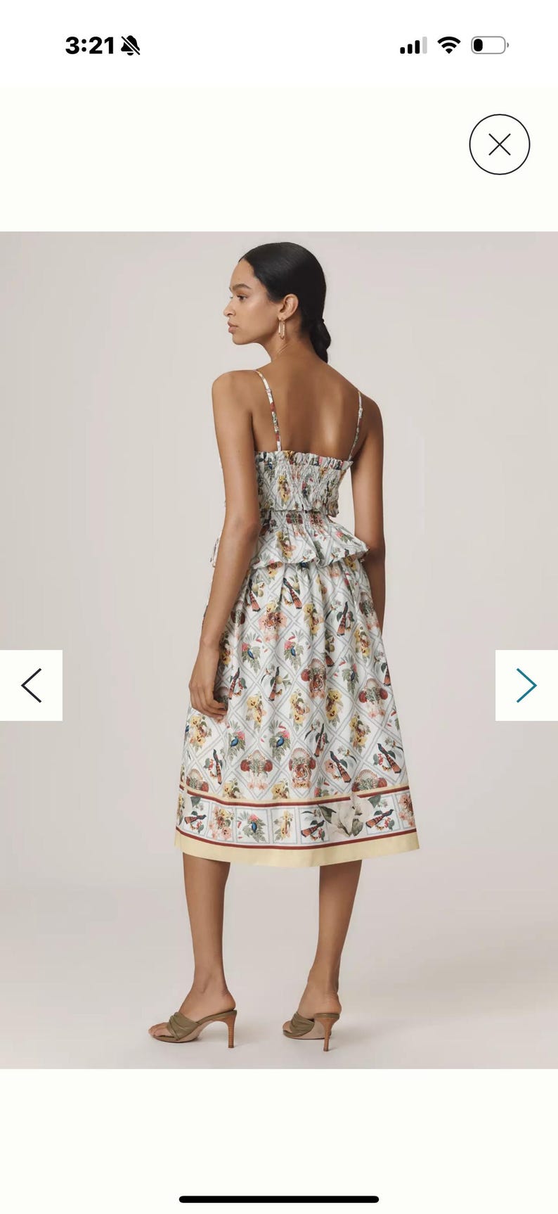 May include: A two-piece dress with a white background and a colourful floral pattern. The top has thin straps and a ruffled hem. The skirt is knee-length with a yellow border. The model is wearing brown heels.