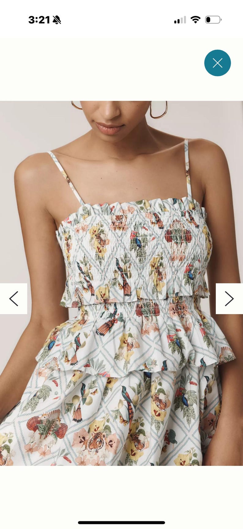 May include: A white dress with a colourful floral and bird print. The dress has a smocked bodice and tiered ruffles. The straps are thin, creating a feminine and summery style.