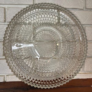 May include: Clear glass serving platter with a diamond pattern and a scalloped edge. The platter is divided into sections, perfect for serving appetizers or snacks. The center has a starburst design.