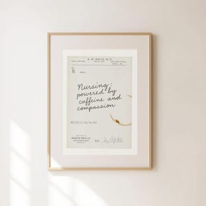 Pode incluir: Impressão emoldurada com um design de receita vintage. O texto diz "Nursing: powered by caffeine and compassion". Uma mancha de café adiciona um toque único. A impressão está em uma moldura de madeira, ideal para um consultório médico ou decoração de casa.