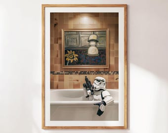 May include: A framed print featuring a Stormtrooper in a bathtub, holding a blaster. The background includes a painting of a sunflower and a lamp. The bathroom has brown tile.