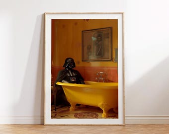 May include: A framed print featuring a yellow bathtub with claw feet. A person in a black Darth Vader costume is seated in the tub. The bathroom has yellow walls and a framed picture. The image is framed in a light wood frame.