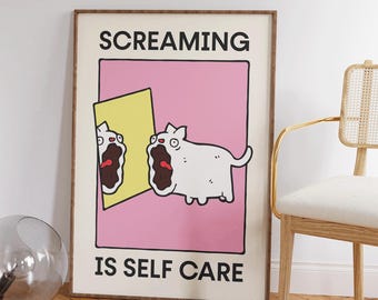 May include: A framed poster with a cartoon cat screaming in front of a mirror. The poster has a pink background with the text "SCREAMING IS SELF CARE" in black letters. The cat is white with a brown mouth.
