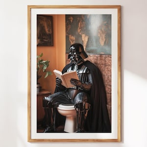 Könnte beinhalten: Gerahmter Kunstdruck mit Darth Vader in voller Montur, der auf einer Toilette sitzt und ein Buch liest. Das Bild hat ein humorvolles Thema, mit einem Holzrahmen und einer hellen Wand im Hintergrund.