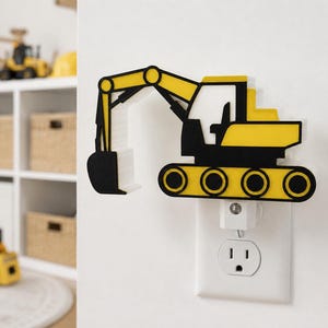 May include: A yellow and black excavator-shaped night light plugged into a standard wall socket. The construction vehicle design features a prominent mechanical arm, a cab, and tracked wheels, all rendered in a flat, layered aesthetic.