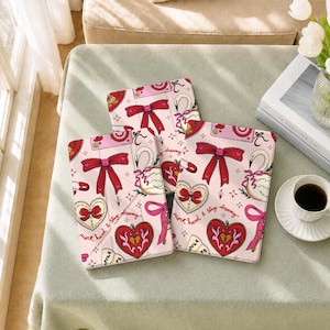 May include: Three rectangular tablet cases featuring a light pink background with a repeating pattern of red bows, white swans, heart-shaped lockets, and safety pins. The text "work hard & stay dreamy" is printed in cursive script on the cases.