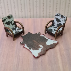 May include: Two miniature chairs with cowhide upholstery and a cowhide rug. The chairs have wooden frames and are arranged facing each other. The rug is brown and white with a distressed look.