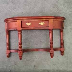 May include: A wooden console table with a single drawer and turned legs. The table is painted a rich reddish brown colour and has gold-coloured drawer pulls.