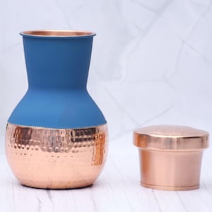 May include: A copper and blue decorative vase with a hammered texture on the copper base. A matching copper container sits beside the vase. The vase has a blue top and a copper base.