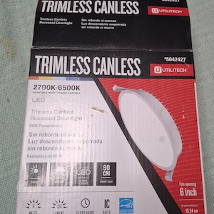 May include: A black and white box for a Trimless Canless Recessed Downlight. The box features the product name, brand, and specifications, including 19 watts, 1200 lumens, and a 6-inch (15.24 cm) opening size.